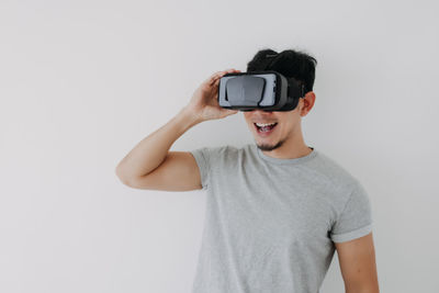 Smiling man using virtual reality simulator against wall