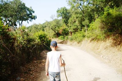 Full length rear view of man walking on road