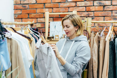 Candid woman shopaholic chooses fashionable clothes in the showroom.