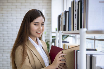 Young woman taking searching books and taking book at a library bookshelf
