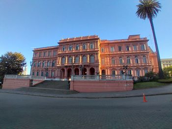 Building by street in city against clear blue sky