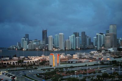 City at waterfront against cloudy sky