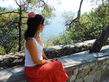 Side view of young woman sitting on retaining wall