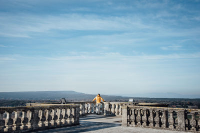 Rear view of woman standing on observation point against cloudy sky