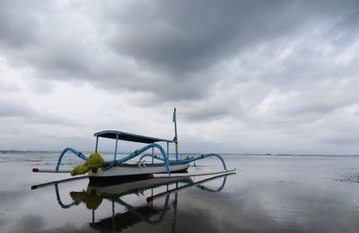 Boat moored on beach against sky