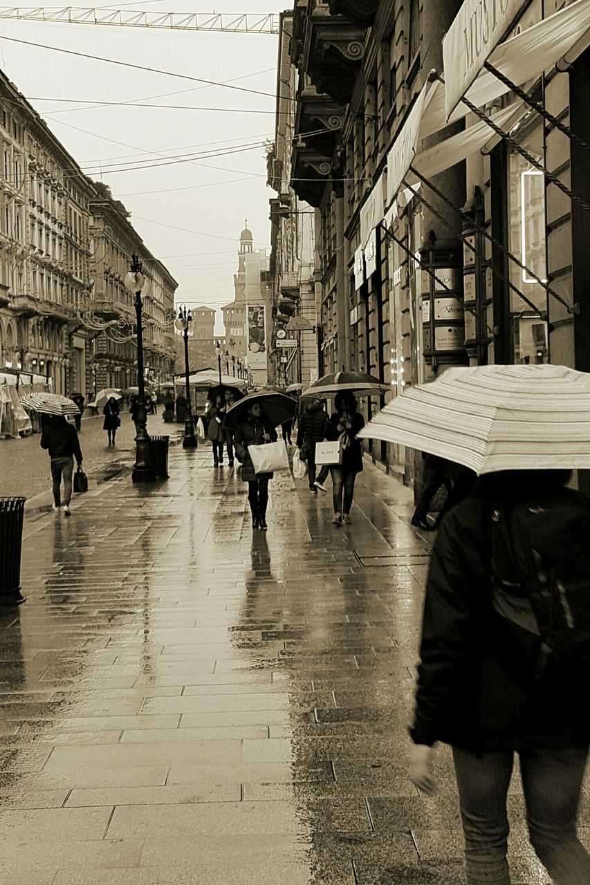 street, city, wet, building exterior, men, people, large group of people, adult, outdoors, water, adults only, extreme weather, day, architecture, only men