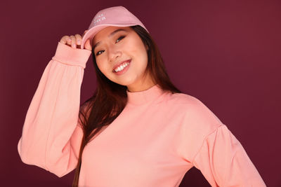 Portrait of smiling young woman against pink background