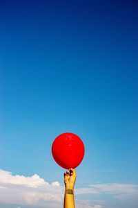 Low angle view of red balloons against blue sky