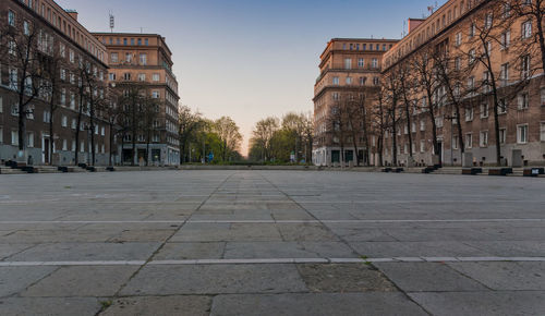 Road by buildings against sky in city