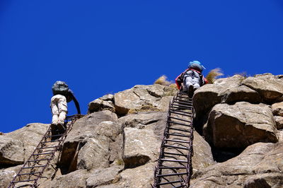 Low angle view of rocks against clear blue sky