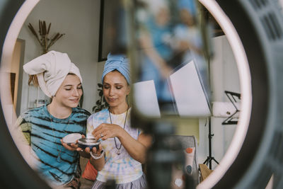 Young woman using smart phone in mirror