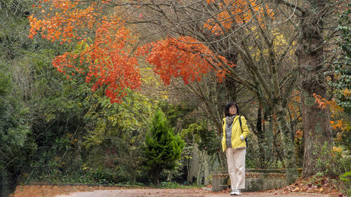 Full length of woman standing in forest during autumn