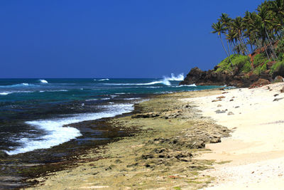 Scenic view of beach against clear blue sky