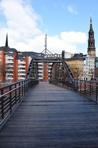 View of footbridge in city against cloudy sky