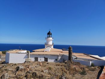 Lighthouse by sea against clear sky
