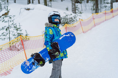 Little boy learning to ride on snowboard standing on ski slope. winter leisure.