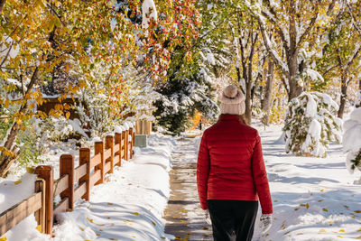 Rear view of person in snow covered park during autumn