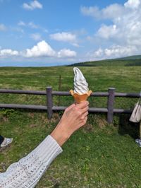 Cropped hand of woman holding umbrella against sky