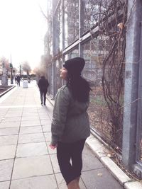 Rear view of woman walking on snow in city