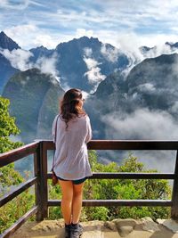 Rear view of young woman looking at mountains while standing at observation point