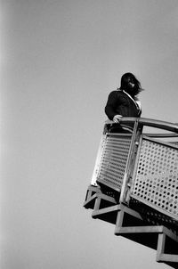 Low angle view of woman standing at observation point against clear sky