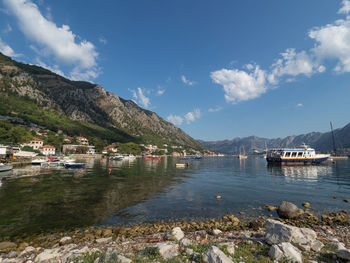 Sailboats moored on sea by buildings against sky