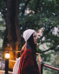 Close-up of young woman standing against trees