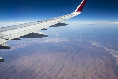 Aerial view of airplane wing over landscape against sky