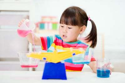 Cute girl holding toy while sitting on table