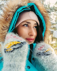 Selfie portrait of a girl in winter clothes and mittens outdoors in winter