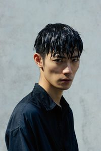 Portrait of young man standing against wall