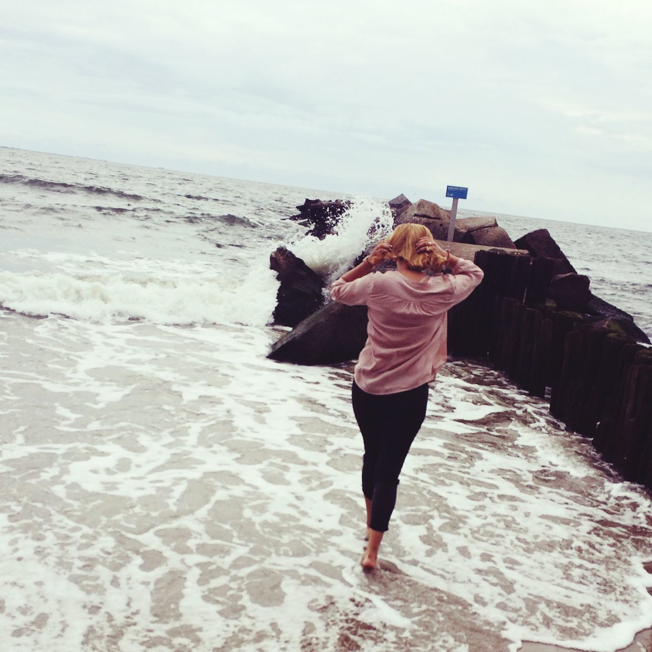 WOMAN STANDING AT BEACH AGAINST SKY