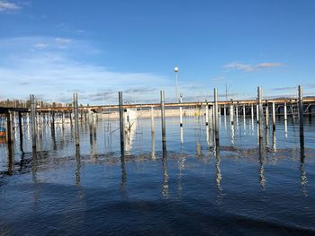 Wooden posts in lake against blue sky