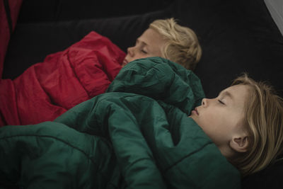 High angle view of brother and sister sleeping in tent with closed eyes