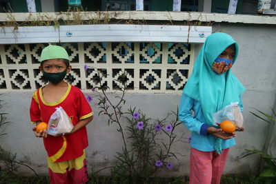 Kids wearing mask holding fruits outdoors