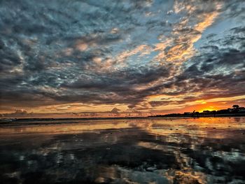 Scenic view of sea against dramatic sky during sunset