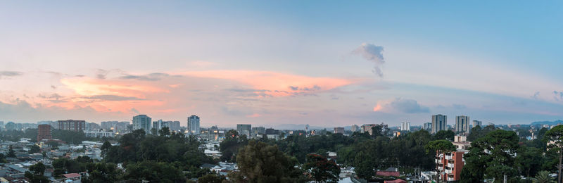 Panoramic view of trees and buildings against sky during sunset