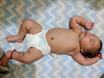 High angle view of baby lying on bed