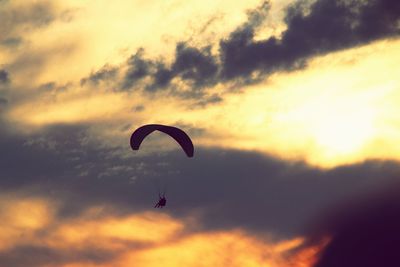 Low angle view of paragliding against sky during sunset