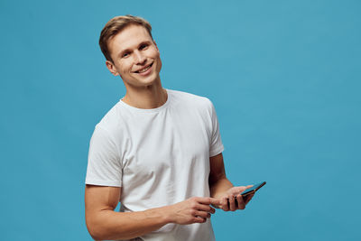 Young man using mobile phone against blue background