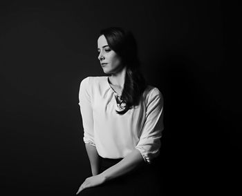 Young woman standing against black background