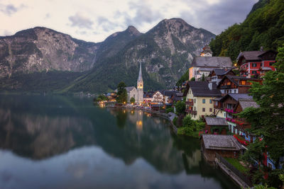 Panoramic view of townscape by lake and mountains against sky