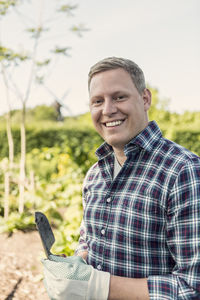 Portrait of happy man holding spatula at community garden