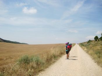 Rear view of person walking on dirt road