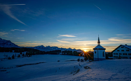 Snow covered land and buildings against blue sky