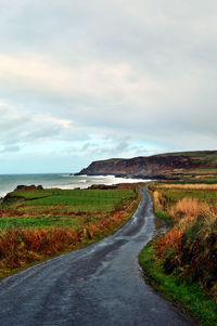 Empty road amidst landscape against sky