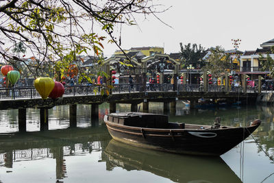 Boats moored by trees against sky
