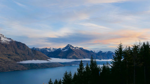 Scenic view of lake by mountains against sky during sunset