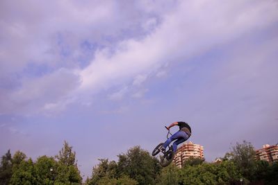 Low angle view of man with bicycle against sky