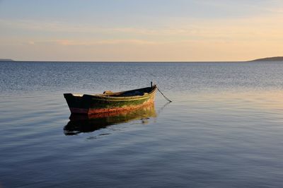 Boat in sea against sky during sunset